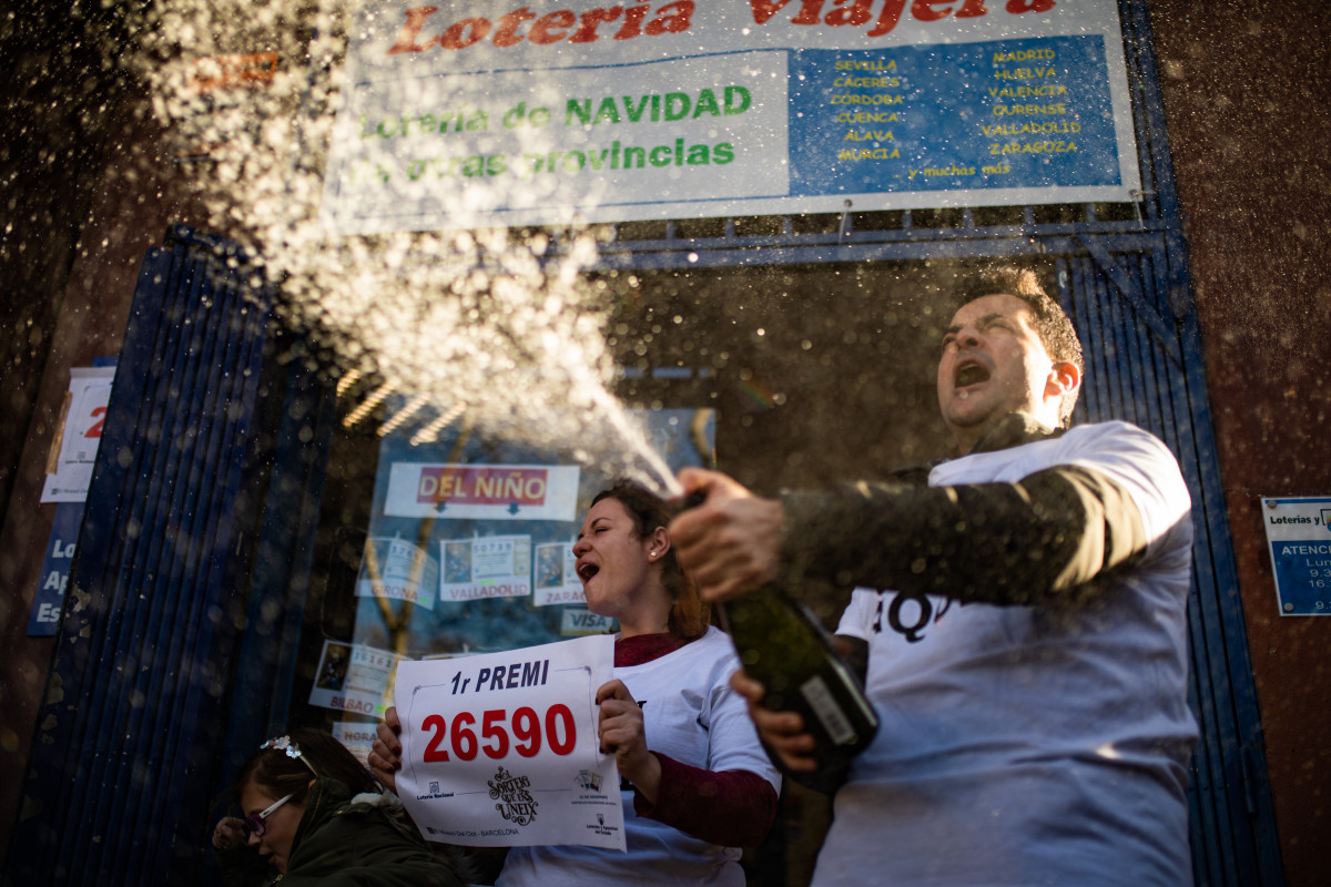 Dos bitlleters celebren que el dècim premiat amb el primer premi de la loteria de Nadal, la grossa de la Loteria, el núm. 26590, s'ha venut al seu establiment, Barcelona /Catalunya (Espanya), 22 de 