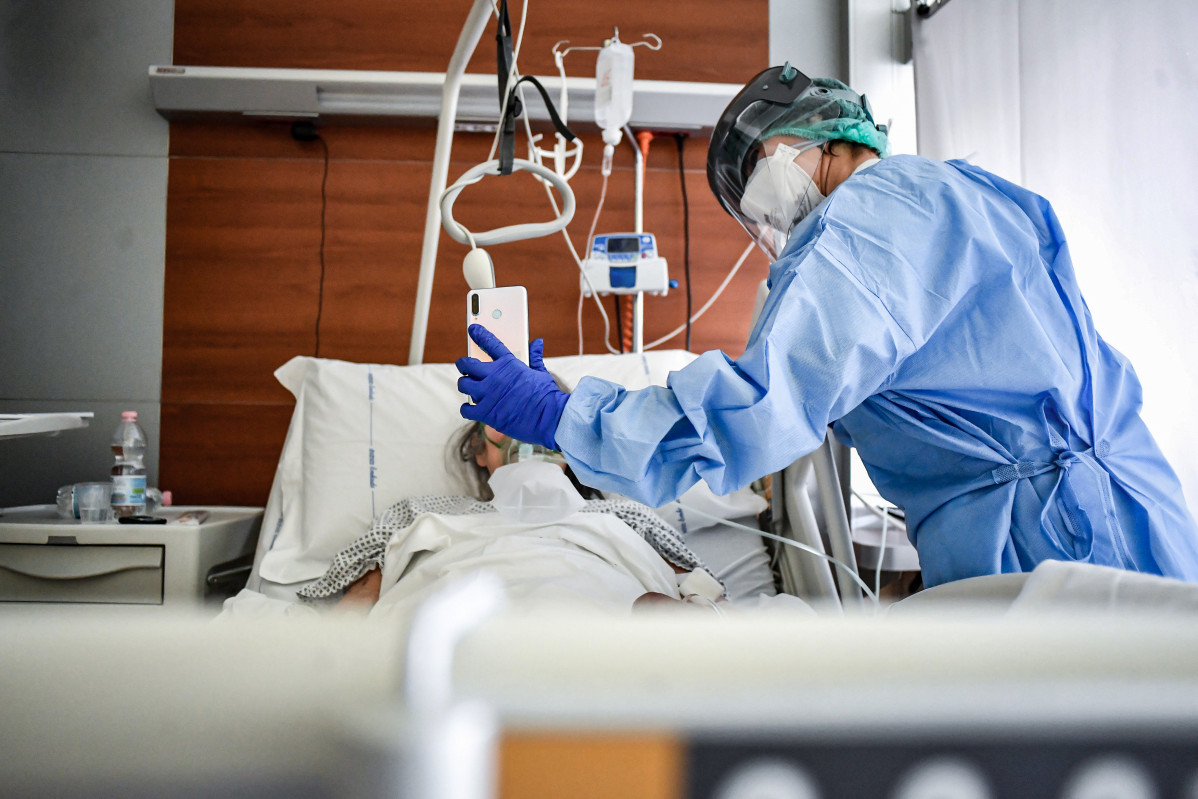Un médico sujeta un móvil mientras un paciente habla con un familiar