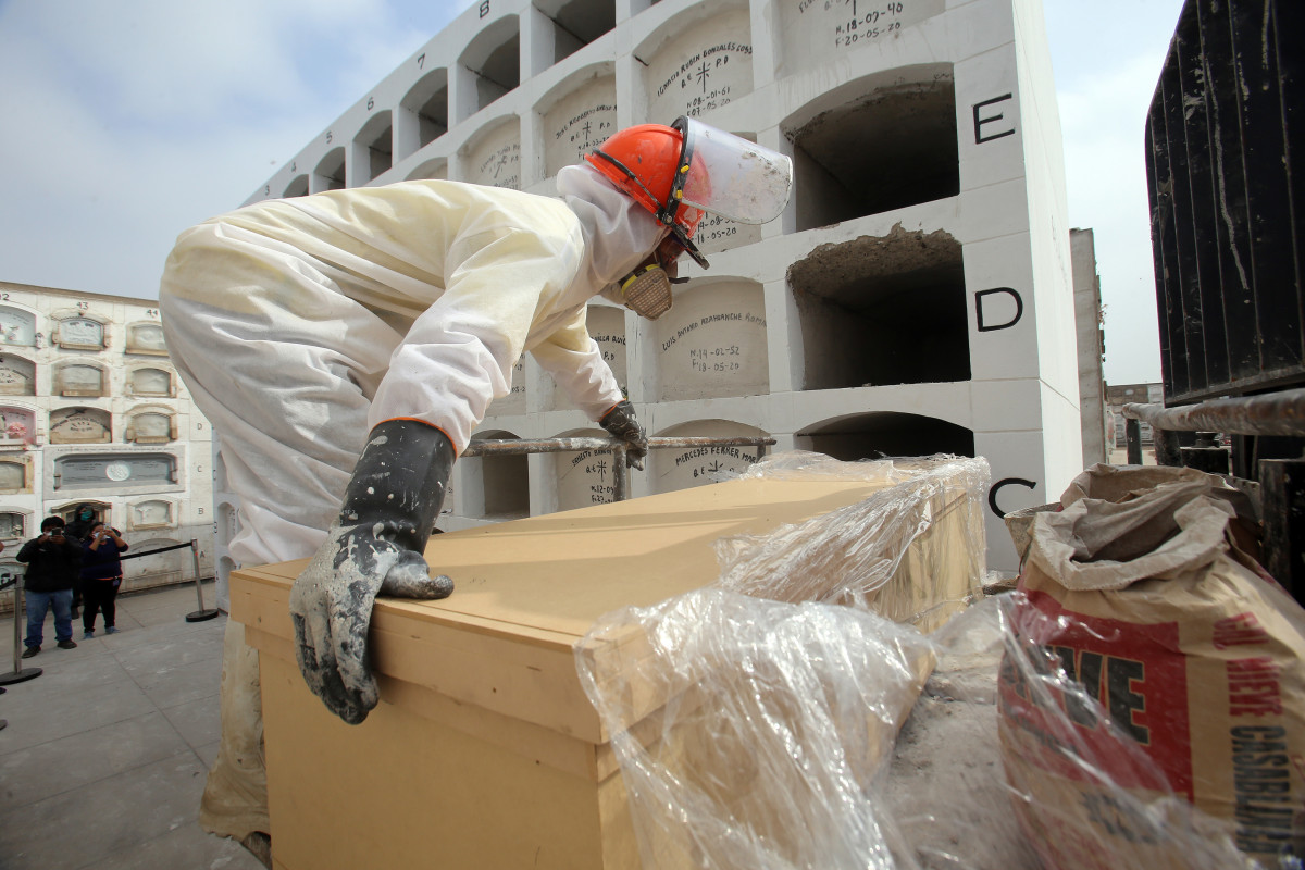 Un trabajador del cementerio de 'El Ángel', en Lima, Perú, coloca el ataúd de una víctima de la COVID-19 en uno de los nichos recién construidos para albergar el alto número de cadáveres que ll