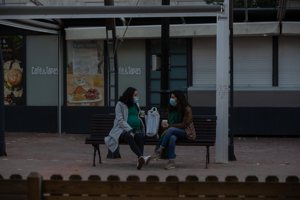 Dos mujeres charlan sentadas en un banco, en Barcelona, Catalunya (España), a 21 de diciembre de 2020.