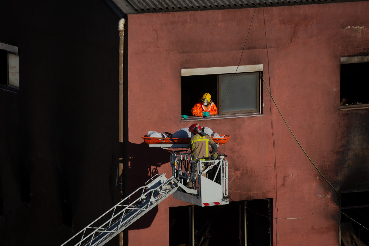Bomberos retiran el cadáver de una de las personas fallecidas en el incendio de ayer en la nave okupada del barrio de Gorg, en Badalona, Barcelona, Catalunya (España), a 10 de diciembre de 2020.