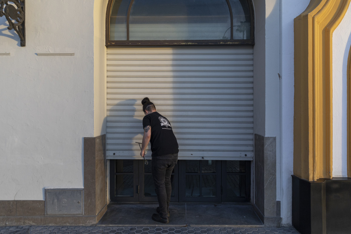 Un hostelero echa la persiana de su establecimiento, tras la nueva medida de restricción que obliga al cierre de toda actividad no esencial a partir de las 18 horas,