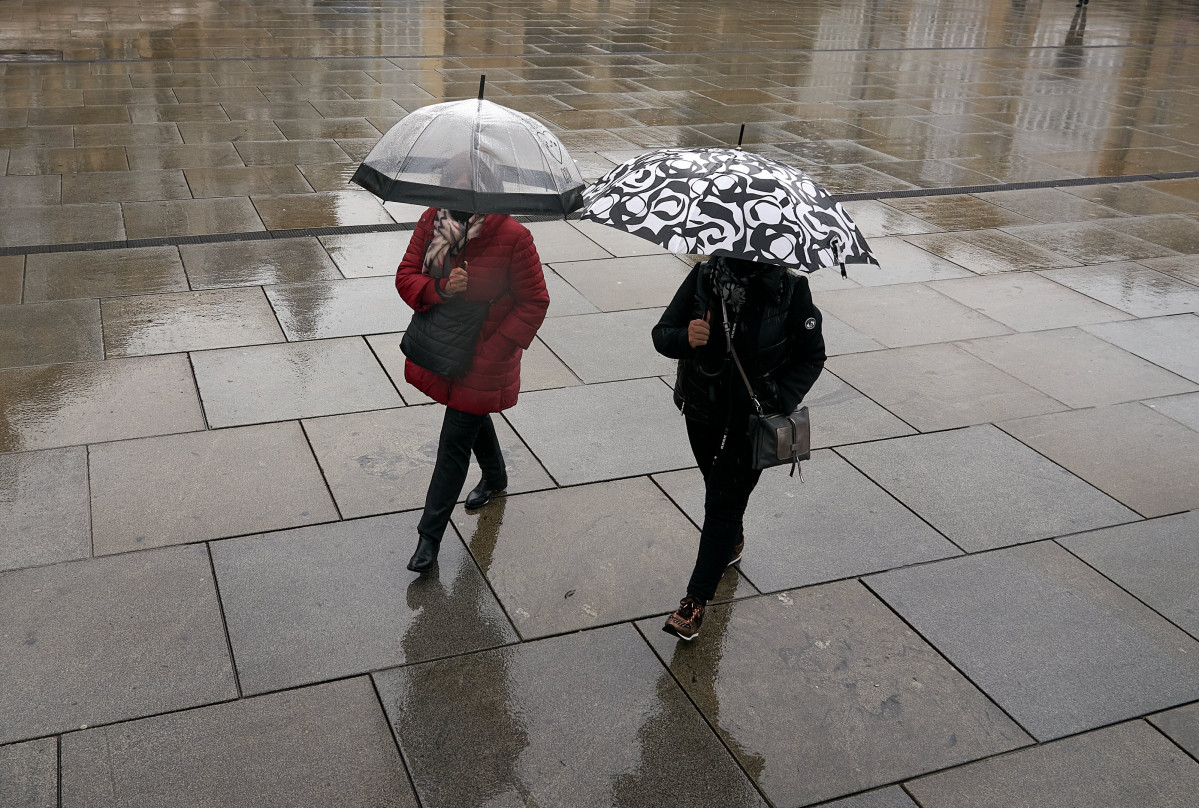Archivo - Dos personas se refugian con un paraguas de la lluvia en Vitoria, País Vasco (España), a 19 de marzo de 2021. Para la jornada de hoy, está activado el aviso amarillo por debajo de los 1.0