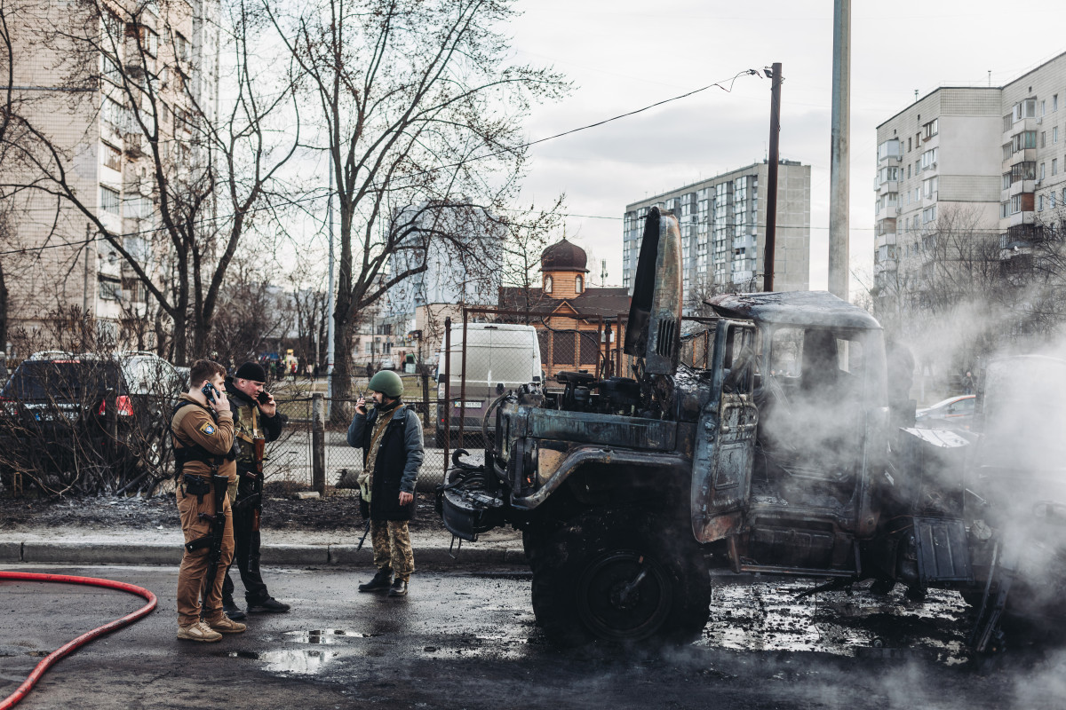 Varios soldados del ejercito ucraniano observan el vehículo militar de su ejército calcinado, a 25 de febrero de 2022, en Kiev (Ucrania). Los soldados rusos han entrado en Kiev para realizar combate