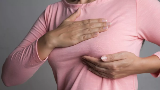 0 WomanhandcheckinglumpsonherbreastforsignsofbreastcancerongraybackgroundHealthcareco