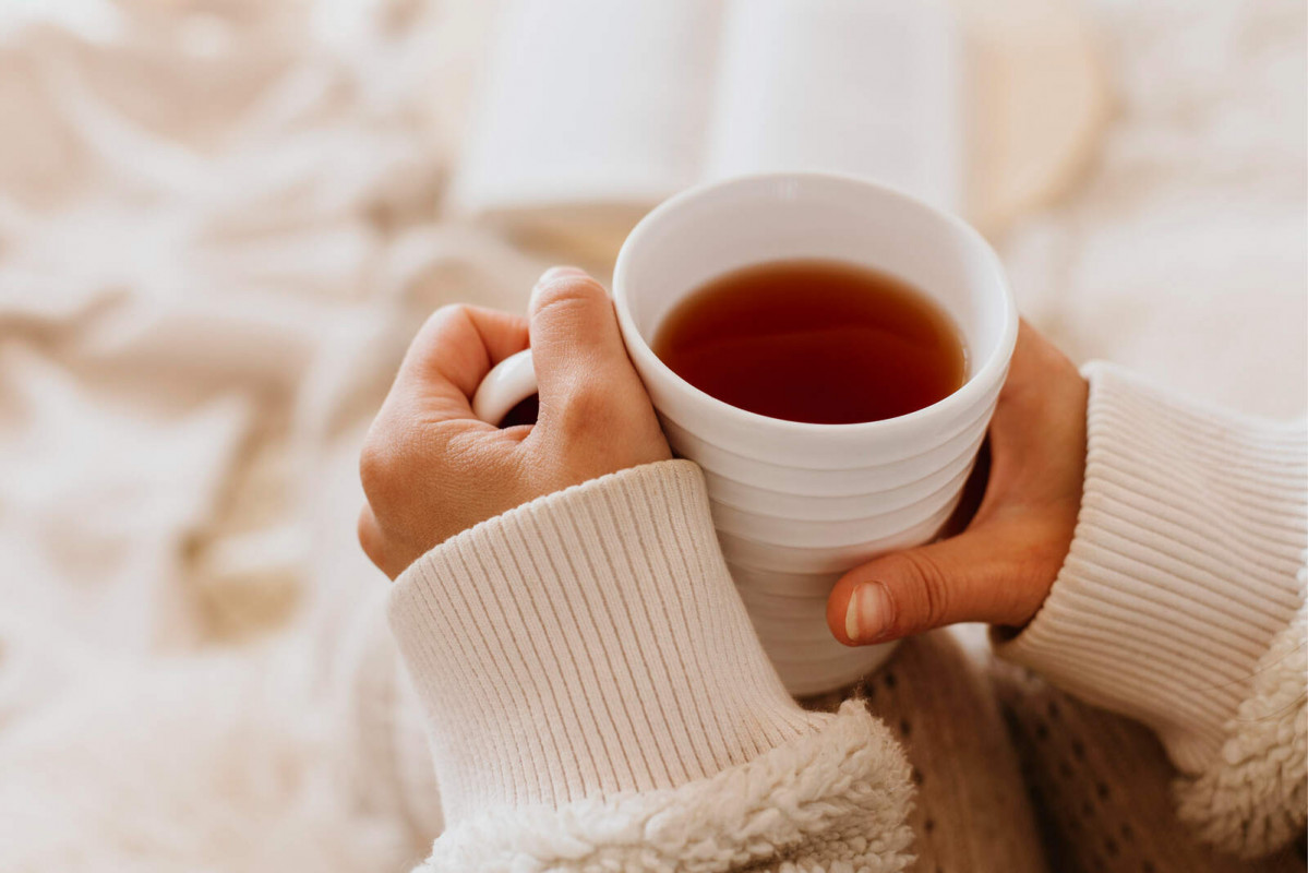 Young woman holding cup tea while enjoying winter holidays 1600 1067