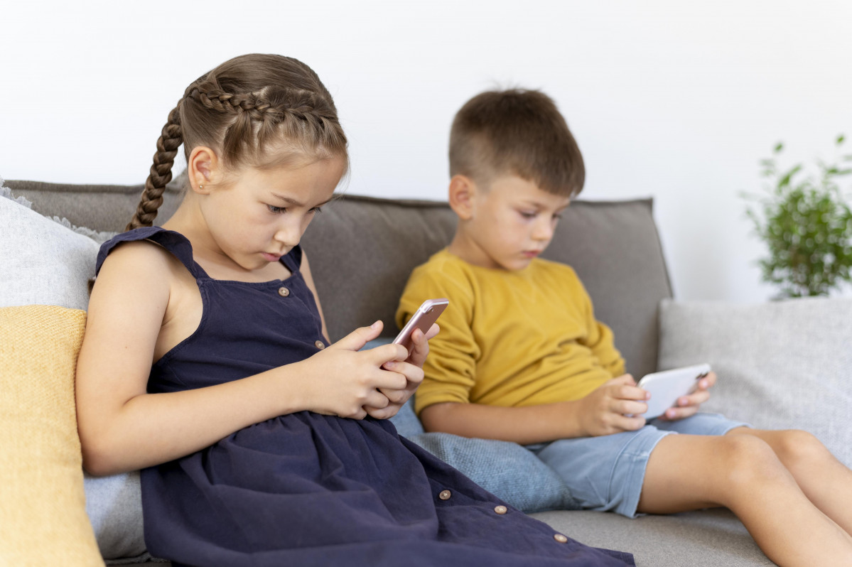 Ninos de tiro medio con dispositivos en interiores