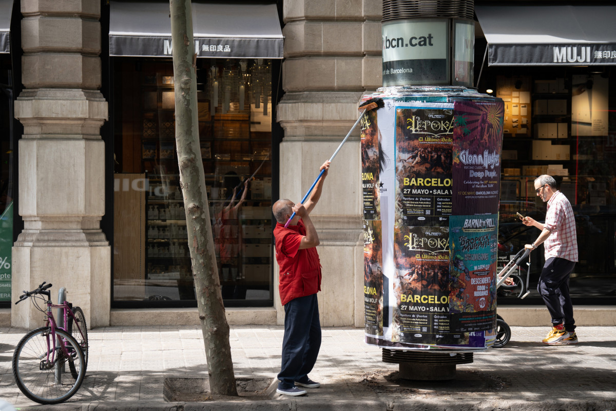 Archivo - Un operario pega carteles en Barcelona