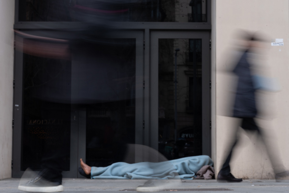 Imagen de archivo - Varias personas pasan delante de una persona sin hogar, en Barcelona