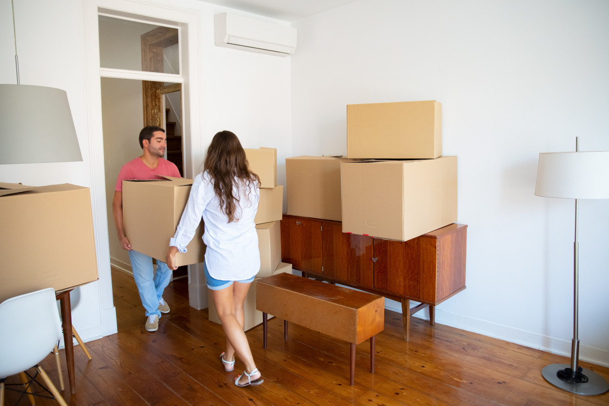 Family couple leaving their apartment carrying carton boxes furniture