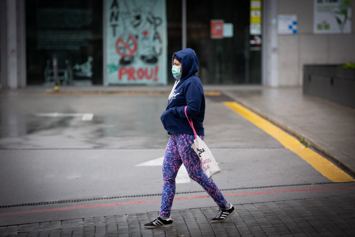 Una dona passa pels voltants de l'Estació de Barcelona Sants durant el dia en què entra en vigor la limitació total de moviments fora de perill dels treballadors d'activitats essencials, mesura adoptada ahir pel Govern com a prevenció de l'