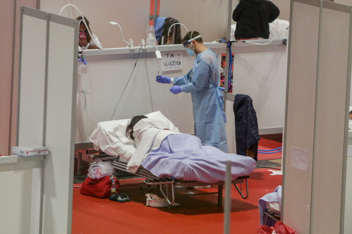 Un sanitari protegit amb mascareta atén una pacient ingressada per coronavirus a l'Hospital de Campanya muntat al recinte madrileny d'IFEMA, a Madrid, (Espanya), a 3 abril 2020.