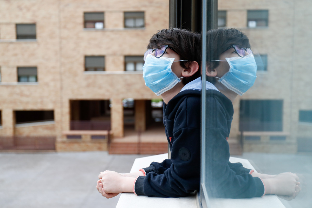 Un nen amb una màscara s'aboca a la finestra de casa durant el confinament pel coronavirus, a Valdemoro / Madrid (Espanya) a 20 d'abril de 2020.