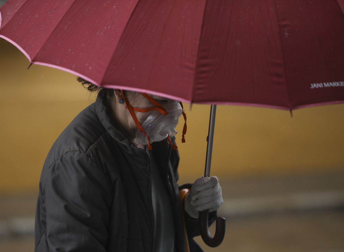 Una dona amb una peculiar màscara es protegeix de la pluja sota el seu paraigua, durant el dia 38 de l'estat d'alarma al país per la crisi de l'coronavirus. A Sevilla (Andalusia, Espanya), a