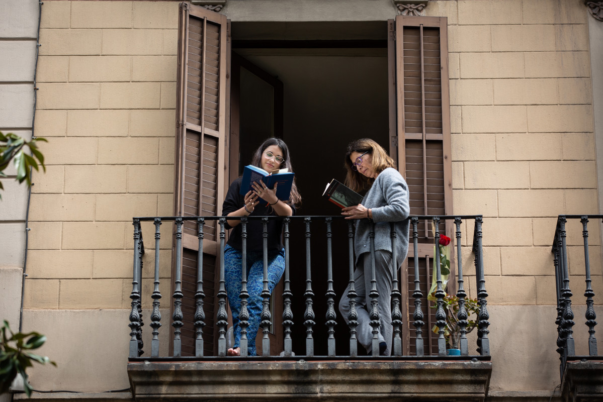 Dos joves llegeixen al balcó de casa seva amb ocasió de la Diada de Sant Jordi, en la qual és costum regalar llibres i roses, a Barcelona / Catalunya (Espanya), a 23 d'abril de 2020.