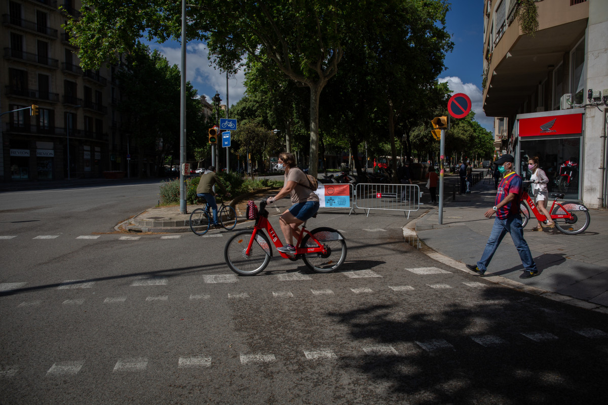 Transeúentes passen a la banda de les tanques instal·lades per tallar el trànsit lateral de la Diagonal. A Barcelona, Catalunya (España), a 13 de maig de 2020.