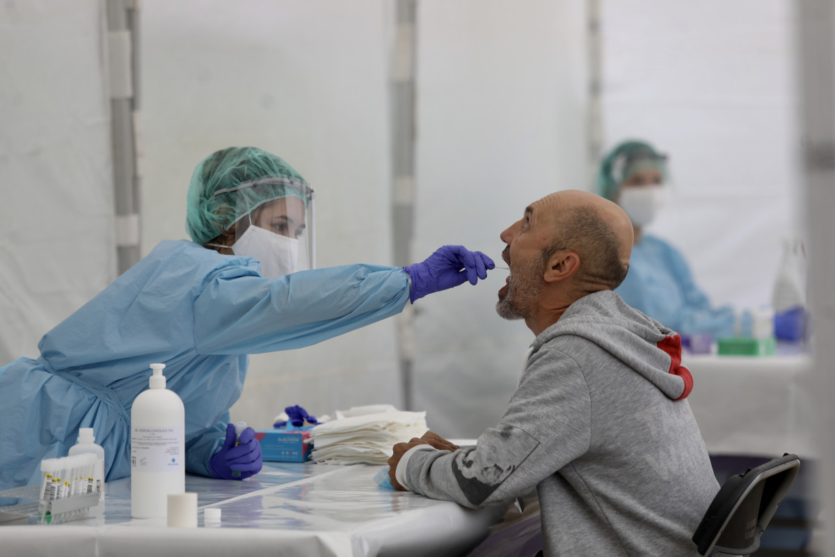 Una sanitària li realitza un frotis bucal a un veí