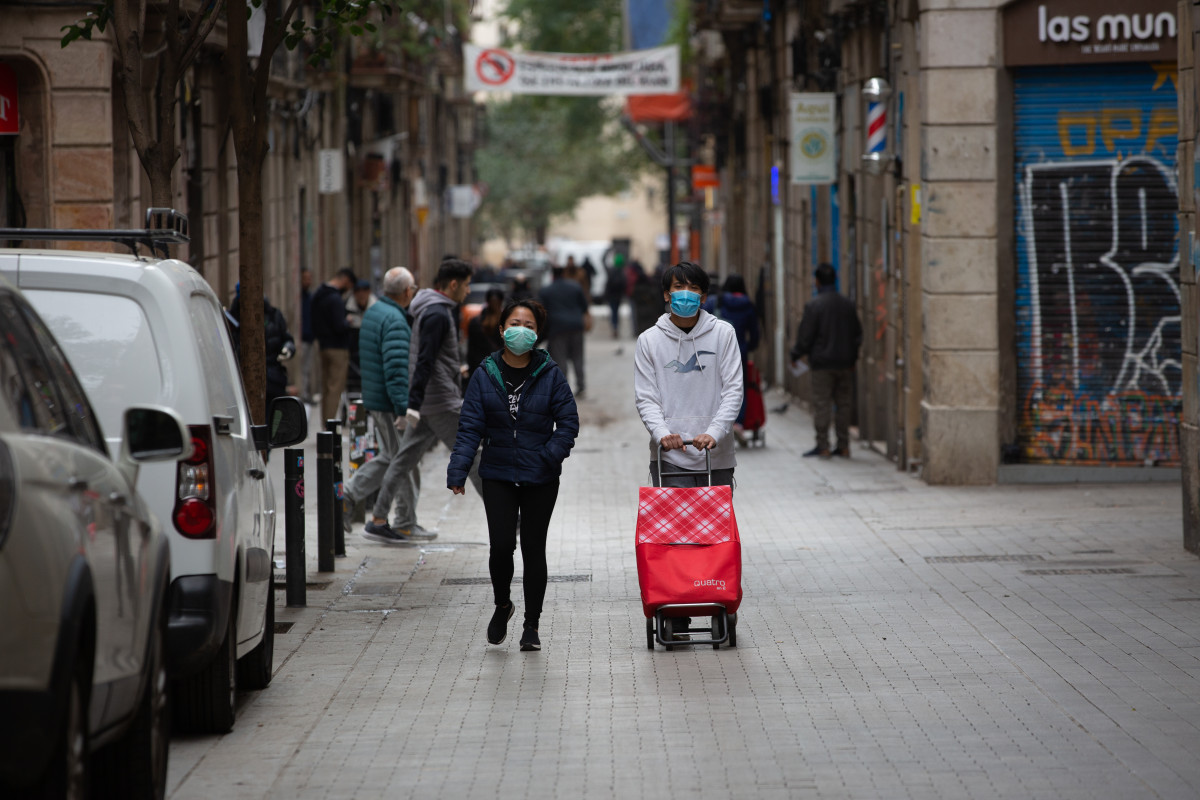 Dues persones protegides amb mascaretes durant el segon dia laborable de l'estat d'alarma pel coronavirus, a Barcelona (Espanya), a 17 de març de 2020.