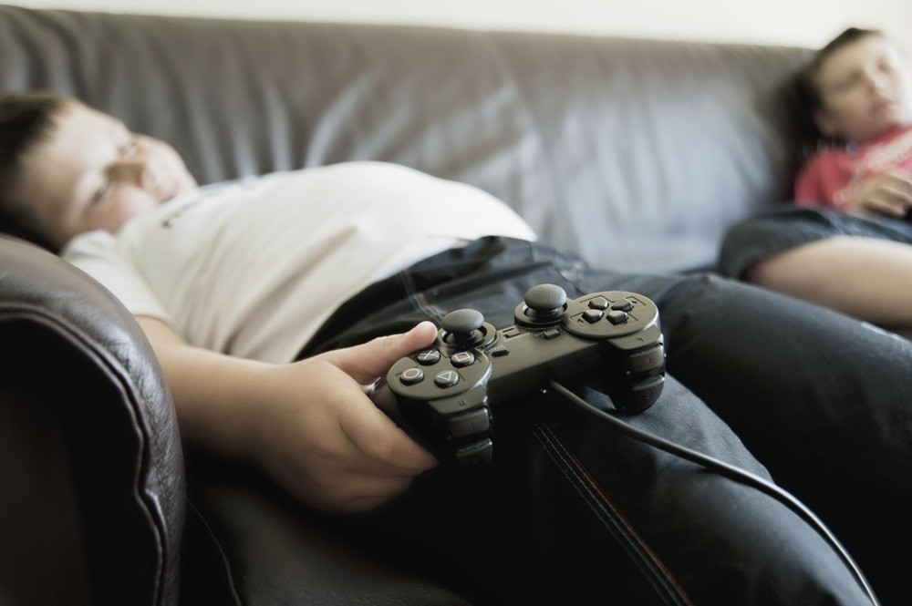 Obesitat infantil. Sedentarisme. Nen amb sobrepès jugant a la videoconsola