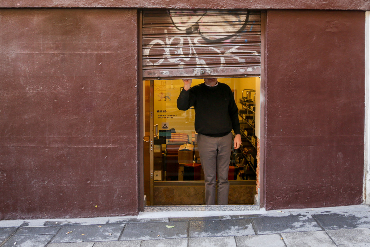 Un autònom baixant la persiana del seu negoci