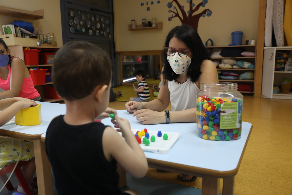 Dos docents imparteixen classes a diversos alumnes en l'Escola Infantil El Tren de la Maduixa, el dia de la seva reobertura després de la parada pel coronavirus a Madrid (Espanya), a 1 de juliol. Les escoles infantils de zero a tres anys, a la Comunitat de Madrid, v
