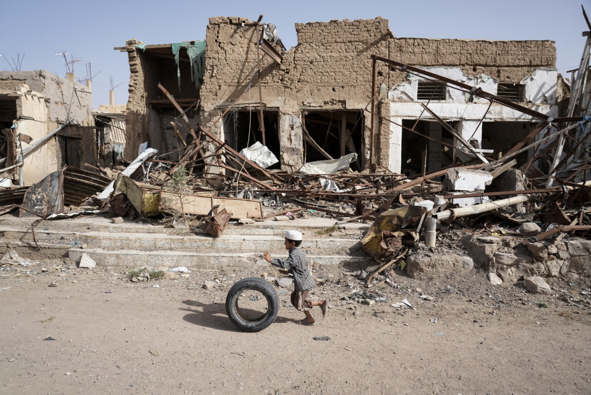 Un nen iemenita davant d'un edifici destruït.
