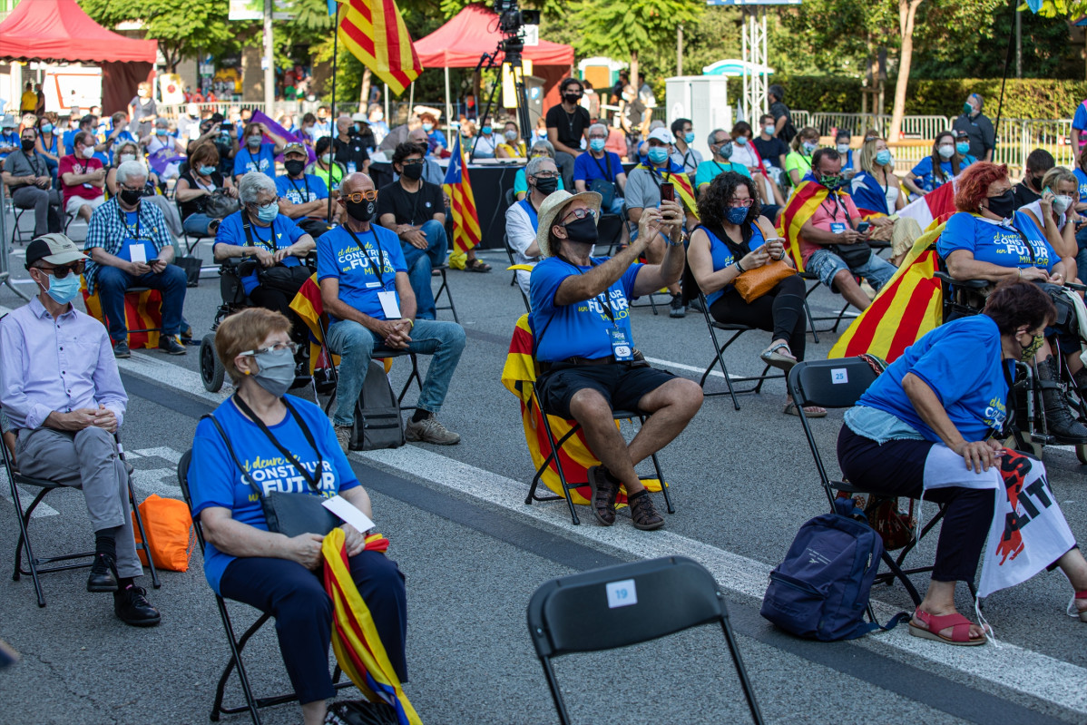 Participants asseguts a les cadires de separació en una concentració de l'ANC, Òmnium i l'AMI per la Diada, a la plaça Letamendi de Barcelona