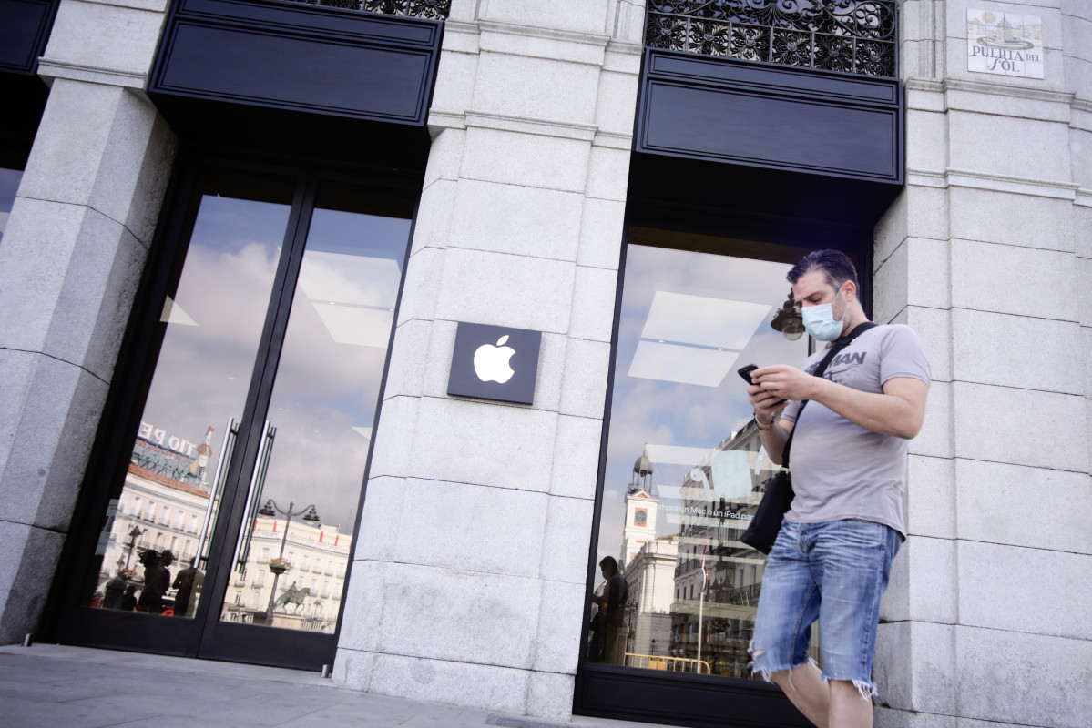 Una persona protegida amb mascareta passa pel costat de la botiga Apple a la Porta de Sol, a Madrid (Espanya) a 24 d'agost de 2020.