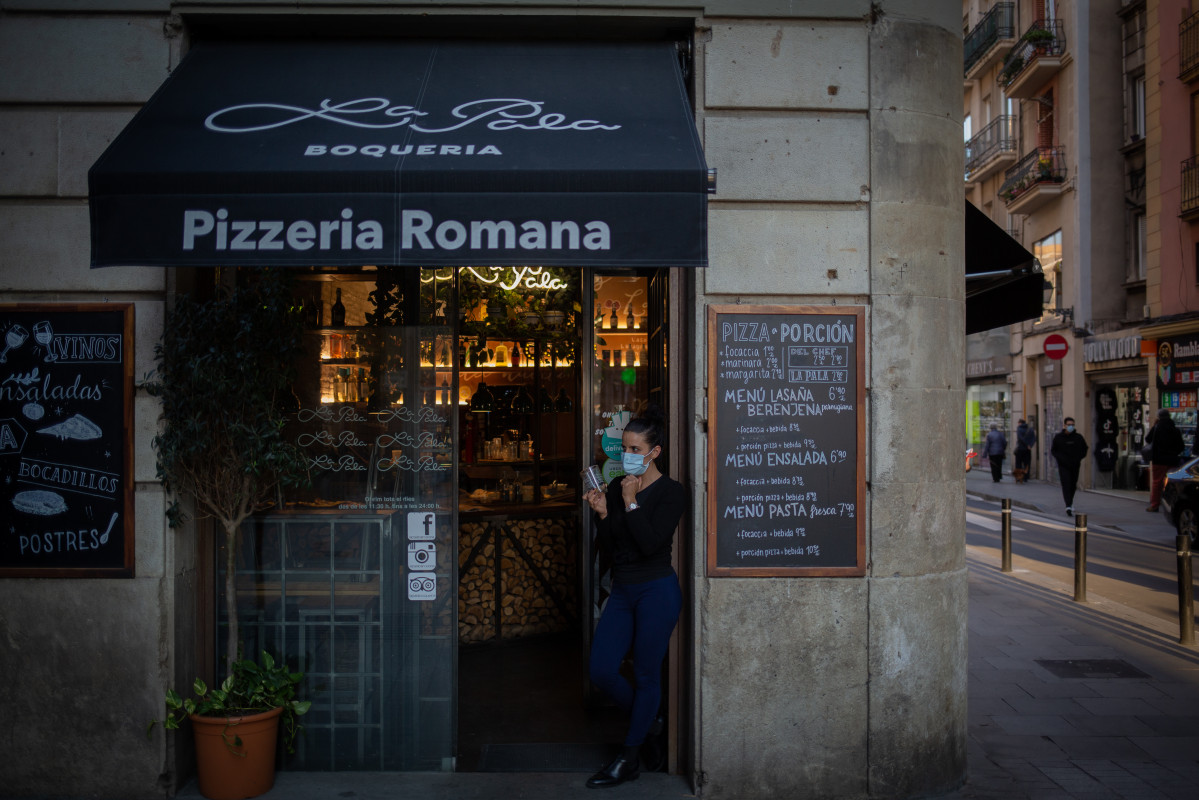Una treballadora observa els voltants del seu establiment de Barcelona, Catalunya (España), després de la paralització de l'activitat durant dues setmanes en bars restaurants, el 16 d'octubre de l'any 2020.