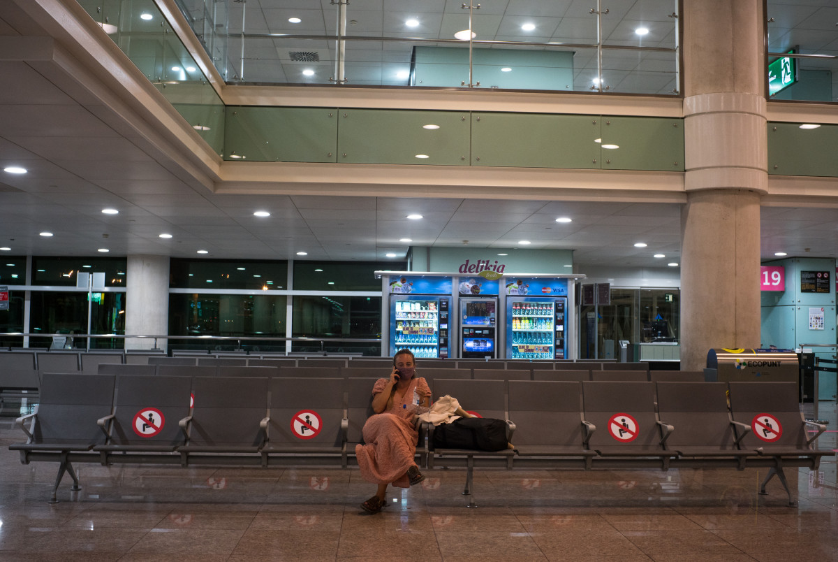 Una dona espera asseguda en uns seients habilitats per preservar la distància de seguretat a l'Aeroport Josep Tarradellas Barcelona-el Prat, a Barcelona, Catalunya, (Espanya), a 12 de setembre