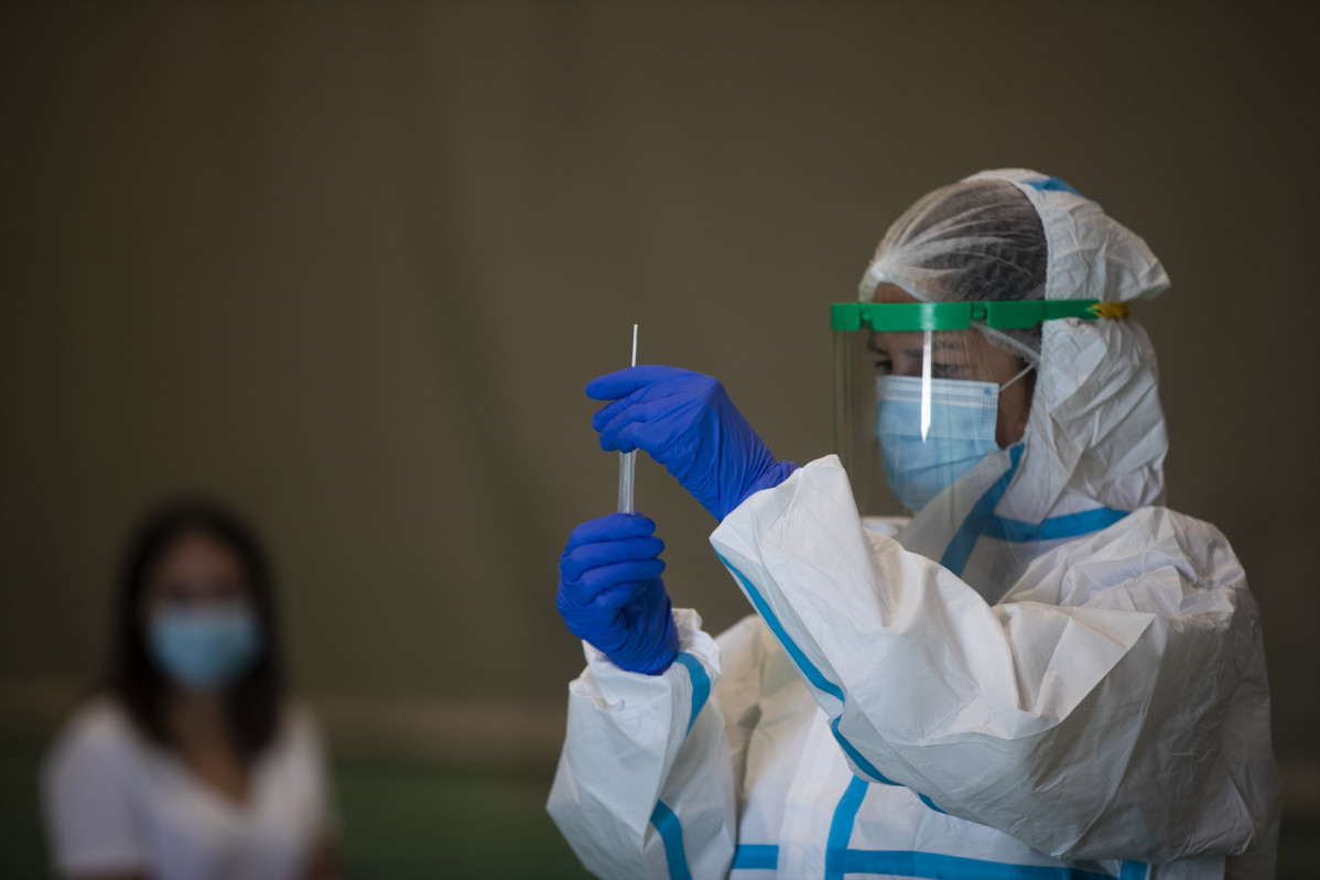Una sanitària atén una dona durant les proves de cribratge de covid-19 amb test d'antígens