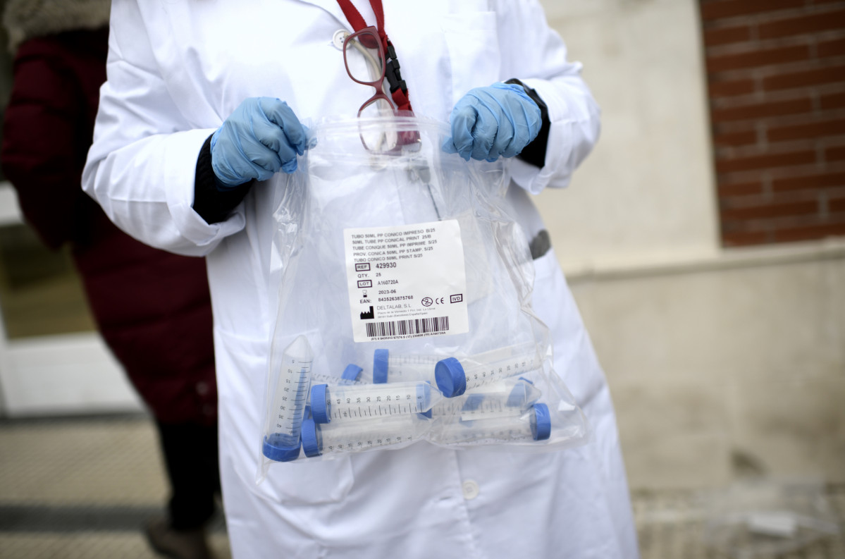 Un sanitari amb tubs d'assaig durant la realització de tests de PCR