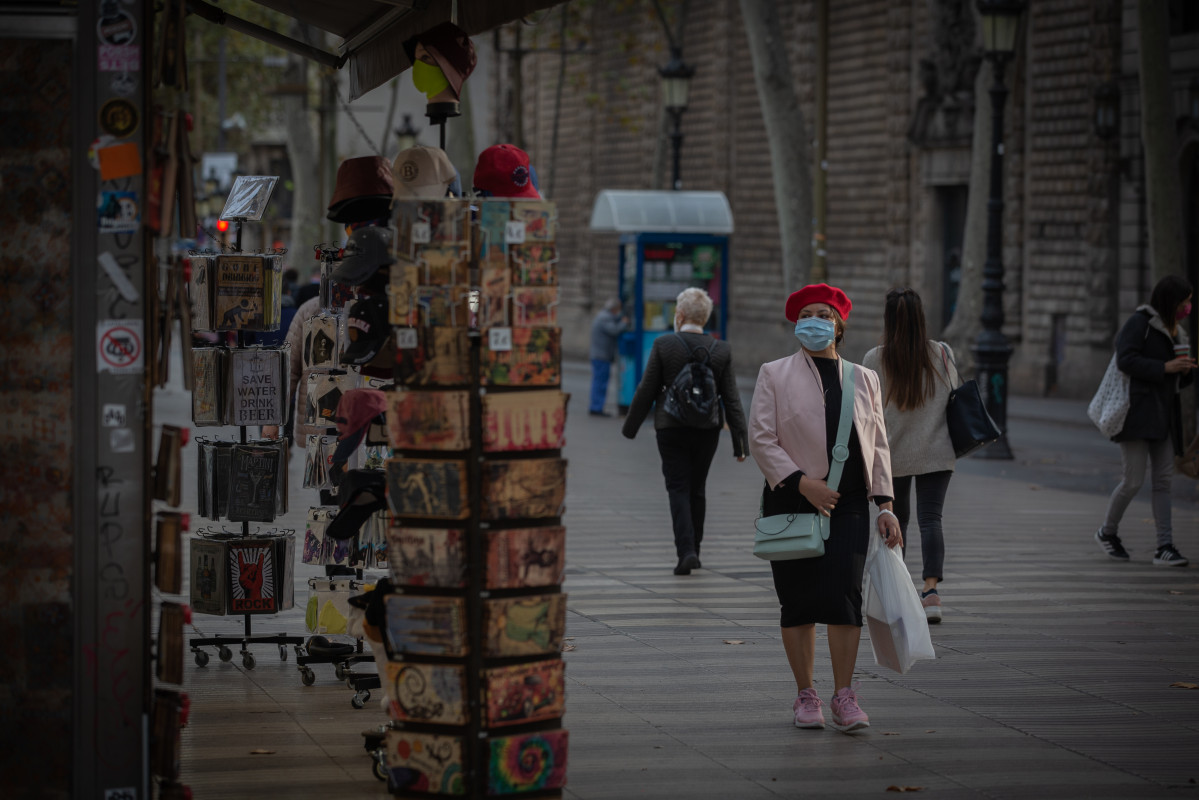 Una dona davant d'una botiga d'articles turístics a Barcelona, Catalunya (Espanya), a 16 de novembre de 2020. El turisme internacional es va desplomar aquest estiu a causa com a conseqüència de l'cor