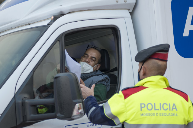 Un Mosso d'Esquadra pide documentación a un conductor durante el control policial por el confinamiento perimetral en la C-17 a la entrada de Ripoll, en Girona (España), a 24 de diciembre de 2020.
