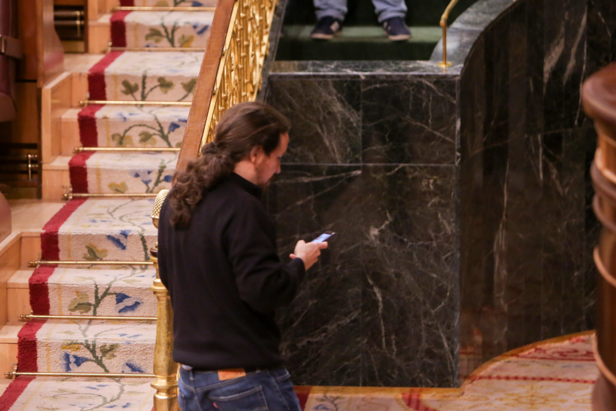 El secretari general de Podem, Pablo Iglesias, sortint de Congrés dels Diputats mirant el seu mòbil.