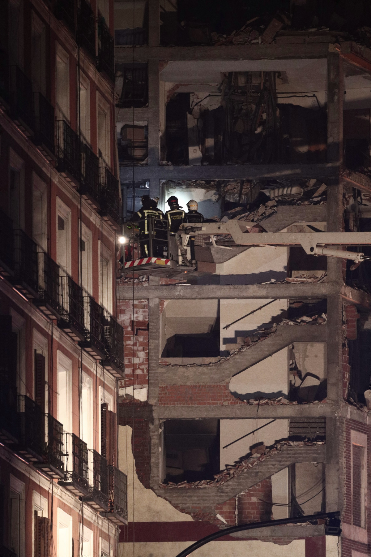 Bombers amb llanternes a l'immoble afectat moments posteriors a una forta explosió registrada carrer Toledo que ha enfonsat diverses plantes de l'edifici, a Madrid, (Espanya), a 20 de gener de 2021. L'explosió s'ha produït minuts abans de les