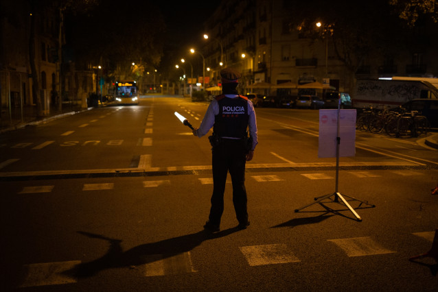 Un mosso d'Esquadra colabora en un control durante el toque de queda impuesto por la crisis sanitaria del Covid-19.
