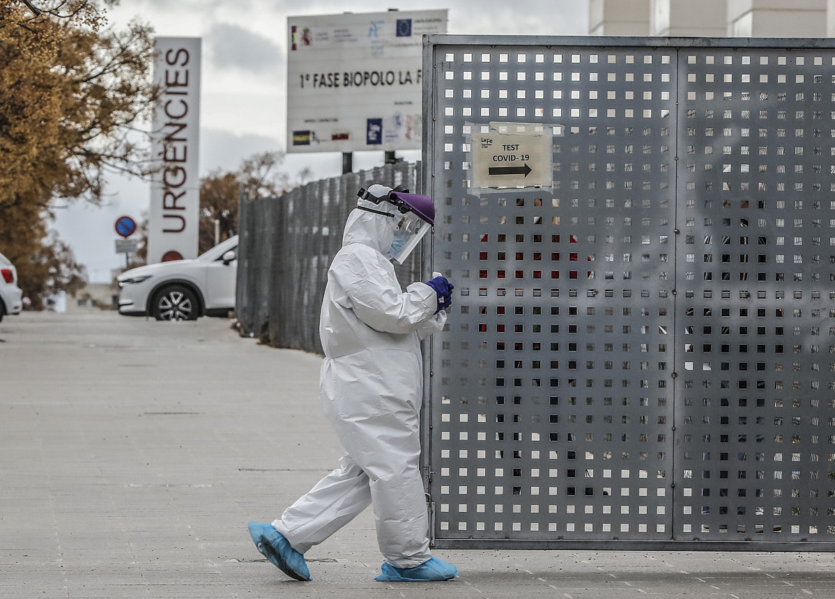 Un sanitari als voltants de la fila de vehicles per realitzar-se una prova PCR de detecció de l'coronavirus a les portes de l'Hospital de Campanya proper a el de La Fe, a València.