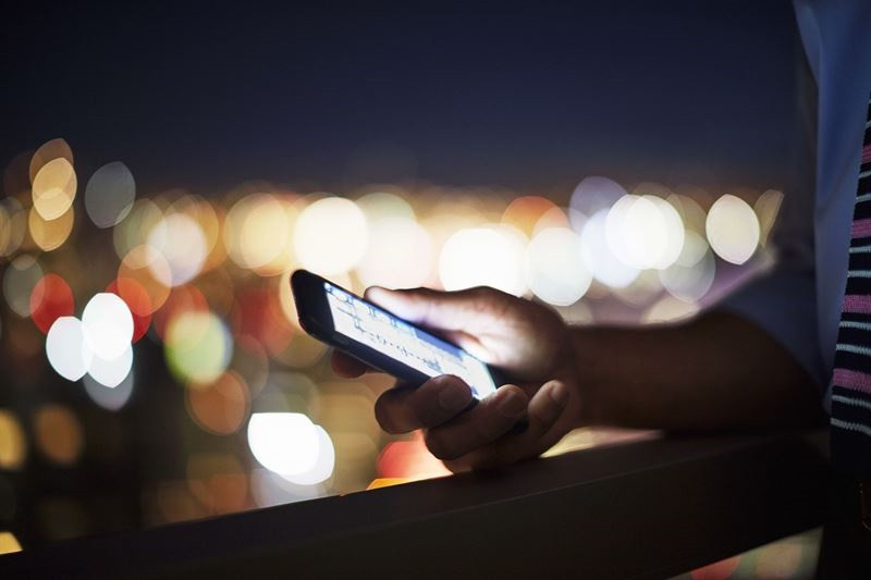 Una persona utilitzant el seu telèfon mòbil (smartphone) a la nit