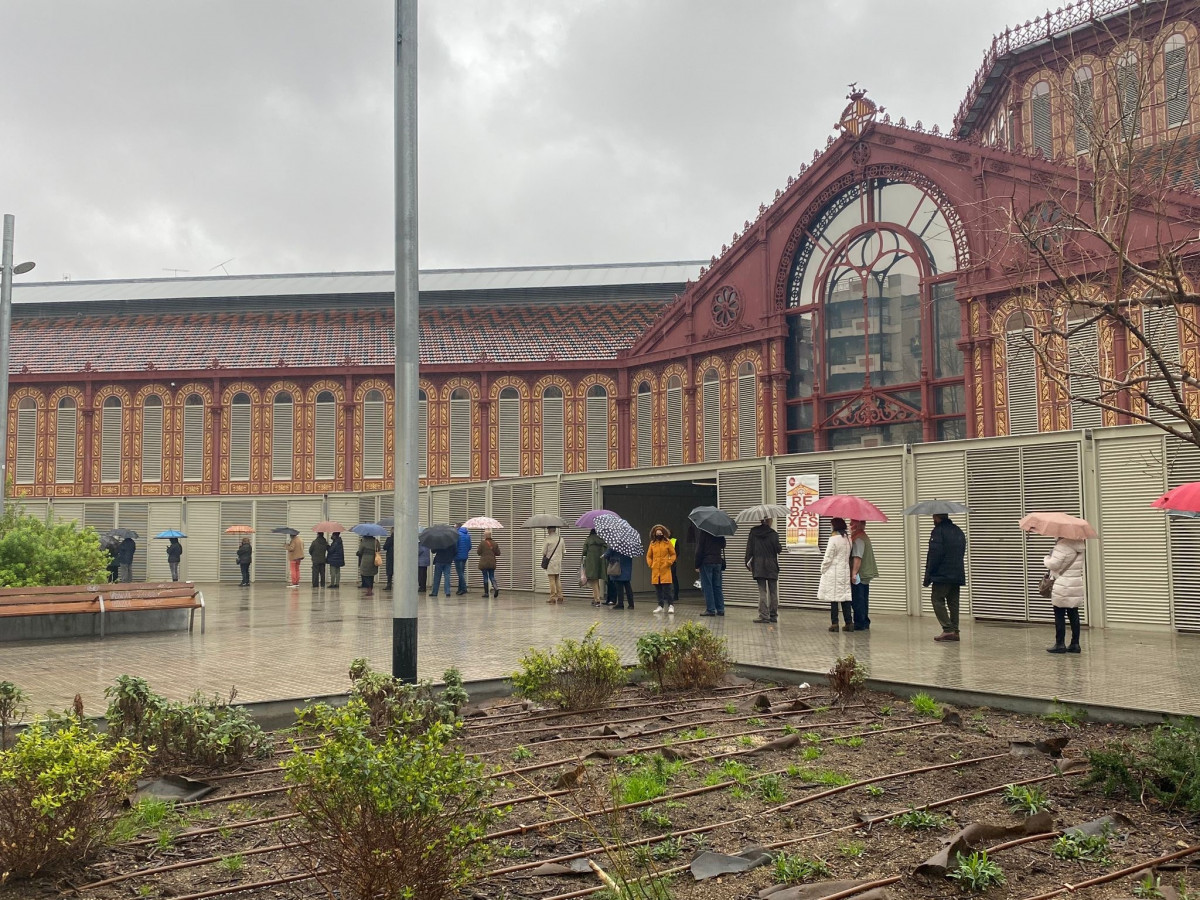 Cua de ciutadans guardant distància de seguretat pel coronavirus esperant a votar al Mercat Sant Antoni de Barcelona en les eleccions catalanes