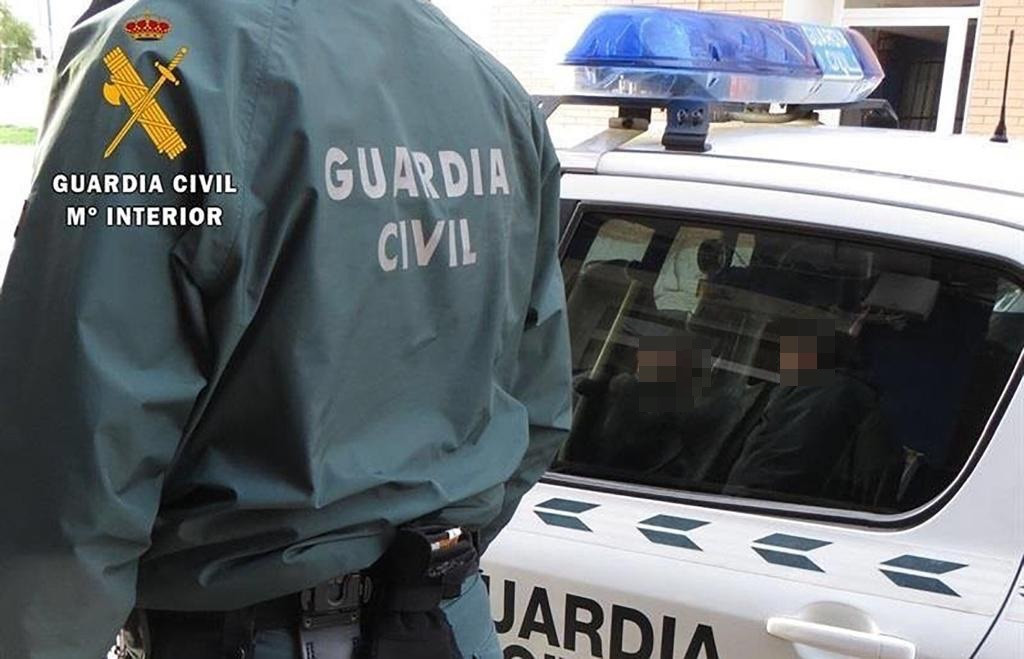 Un agent de la Guàrdia Civil al costat d'un cotxe patrulla.