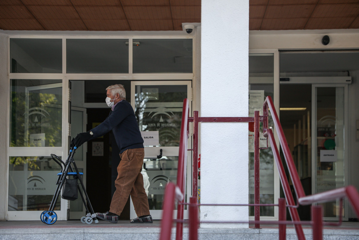 Un home gran passeja amb un caminador a les portes d'un centre residencial a Sevilla.