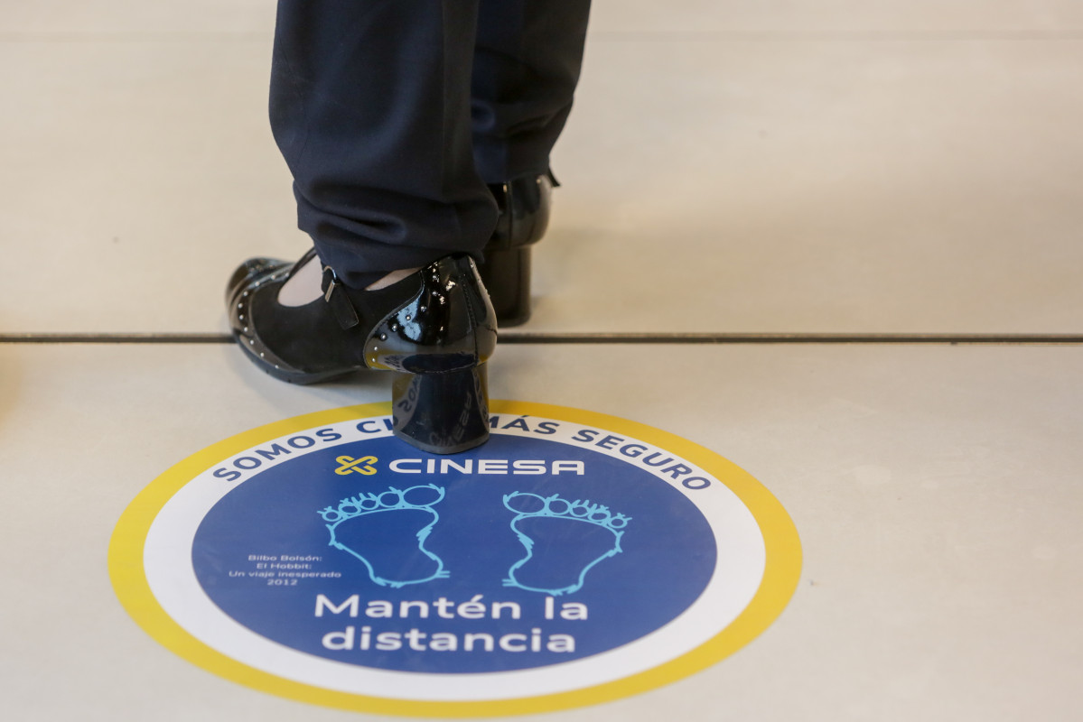 Arxiu - Una persona trepitja un dels cartells indicatius per mantenir la distància de seguretat instal·lats al cinema Cinesa LUXE Xanadú, situat a la localitat madrilenya de Arroyomolino