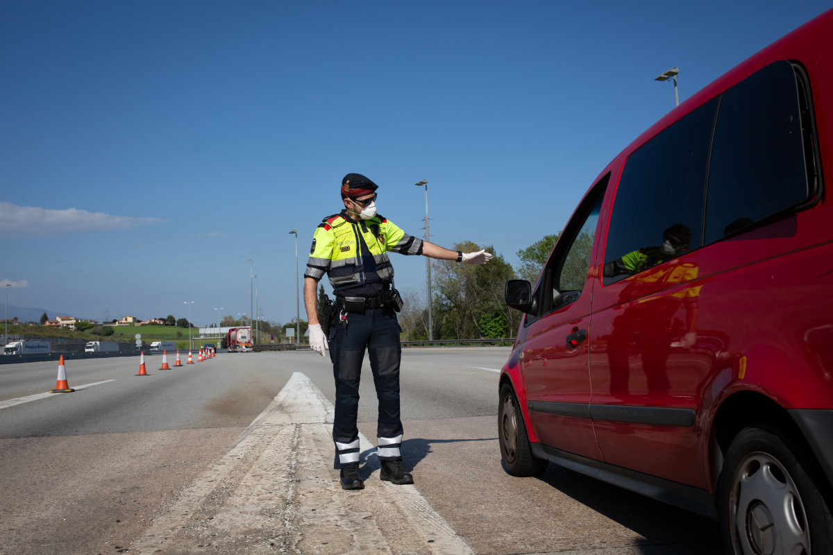 Arxiu - Arxiu - Un agent dels Mossos d'Esquadra protegit amb una màscara en un control al peatge de la Roca del Vallès demana a un conductor el justificant que li permeti la seva sortida, a L