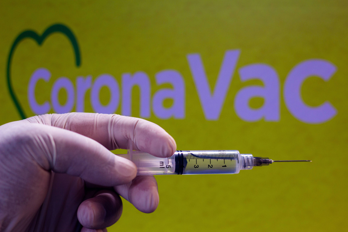 Xeringa davant el logotip de CoronaVac, vacuna xinesa contra el coronavirus