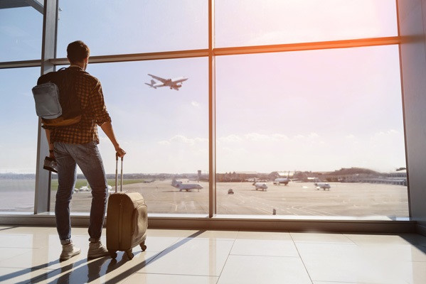 Arxiu - Viatger en una finestra d'aeroport veient enlairar un avió.