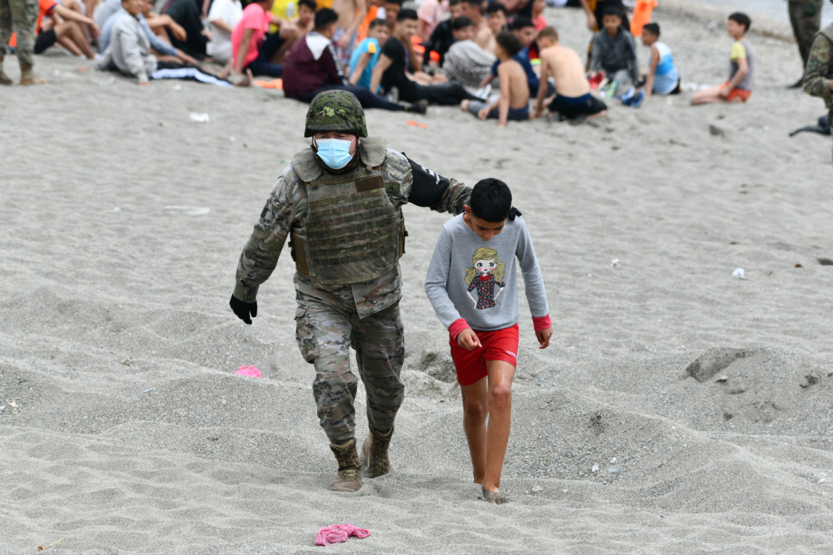 Un militar de l'exèrcit espanyol acompanya a un dels centenars de nens que van entrar a Ceuta de manera irregular la setmana passada.