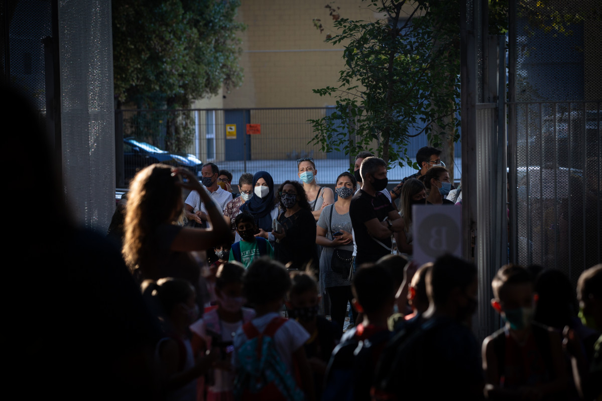 Archivo - Padres y alumnos esperan a las puertas de un colegio (Archivo)