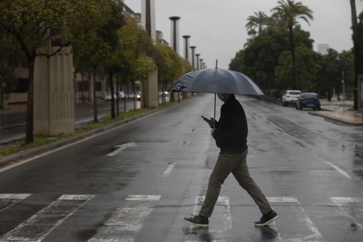 Arxiu - Un home camina protegit de la pluja amb un paraigua