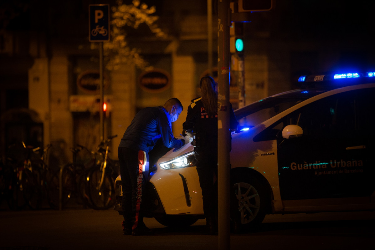 Arxiu - Un home signatura al capó d'un vehicle de la Guàrdia Urbana una multa per saltar-se el toc de queda, a l'Arc de Triomf, Barcelona, Catalunya, (Espanya), a 2 de novembre de 2020.